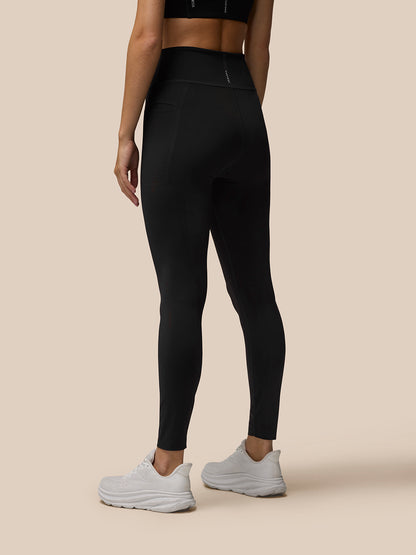 Back view of model in black Flow Movement leggings with a high waistband and a small logo at the waistband