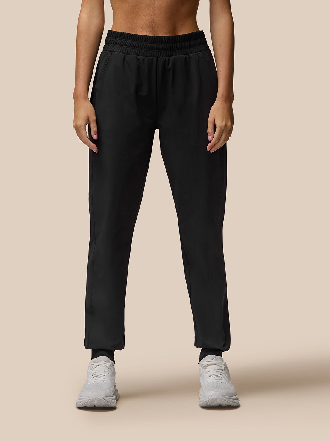 Black Flow Training Joggers on a model with an elastic waistband and cuffs paired with white sneakers