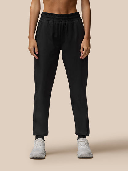 Black Flow Training Joggers on a model with an elastic waistband and cuffs paired with white sneakers