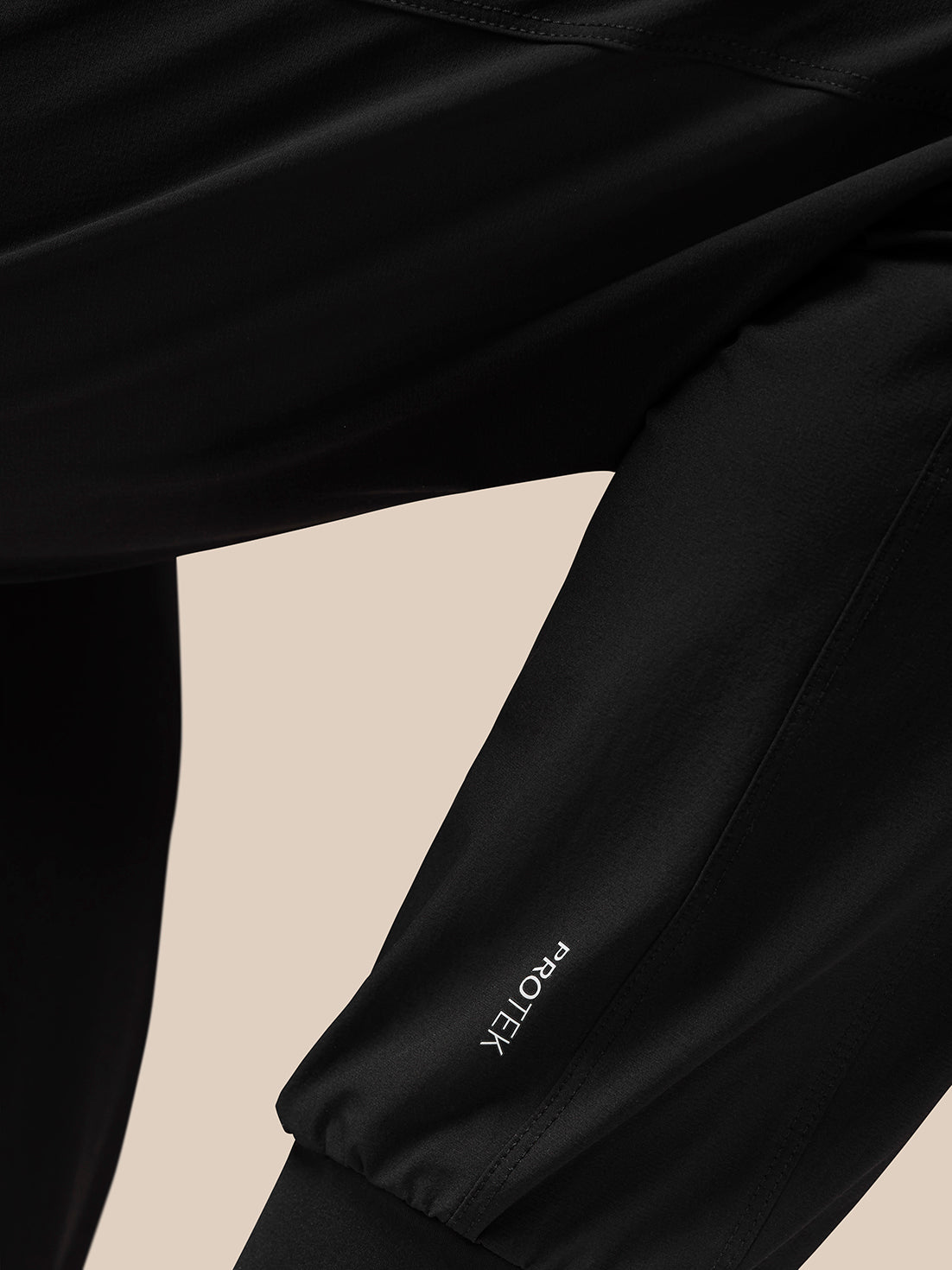 Close-up of the Flow Training Joggers leg in black showing ProTek branding and clean seam details
