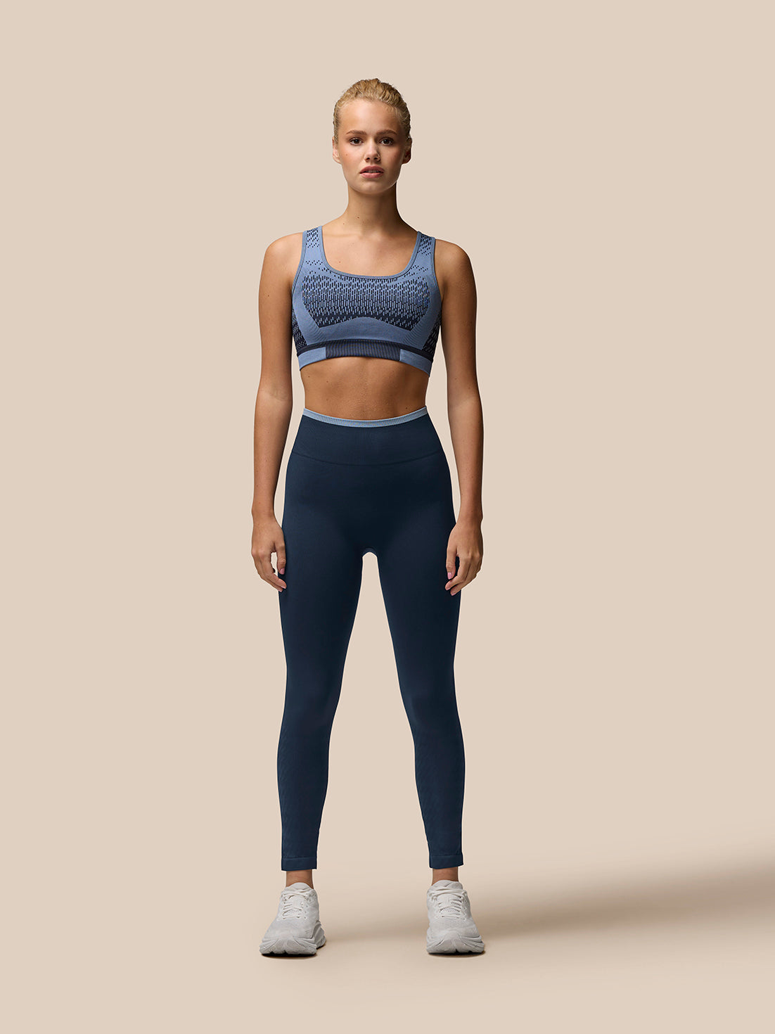 Woman wearing Flow Training ⅞ length seamless leggings in midnight navy with rib waistband.