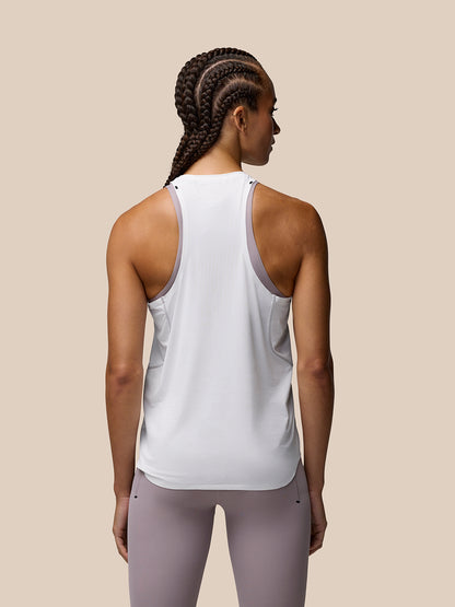 Back view of a woman wearing a white Zone Training Tank Top with lavender trim along the armholes and center back branding