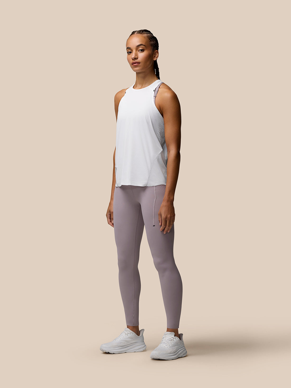 Female model wearing white Zone Training Tank Top with scoop neckline and laser-cut underarm ventilation.