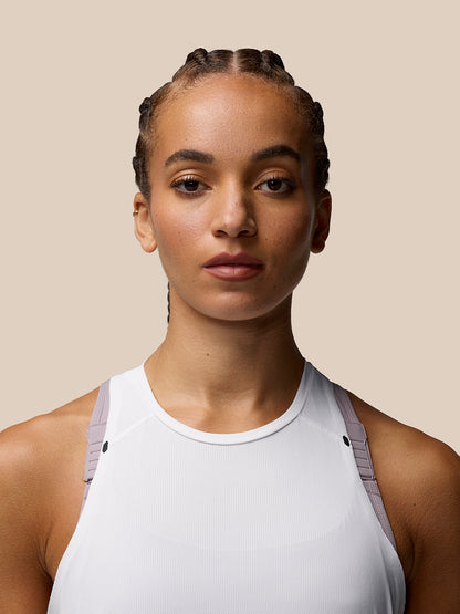 Front view of a woman wearing a white Zone Training Tank Top with lavender trim along the shoulders and a scoop neckline