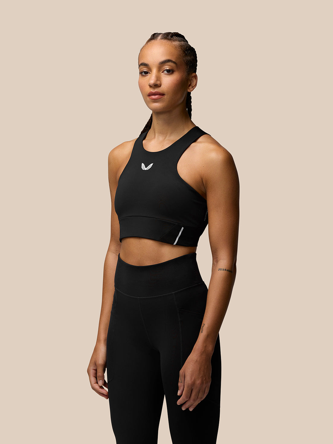Front view of a model wearing a black Apex Training Sports Bra with scoop neckline and chest logo.