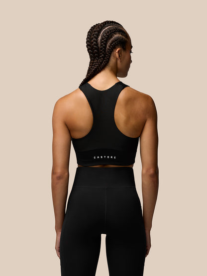 Back view of model in black Apex Training Sports Bra showing racer back and branded back band.