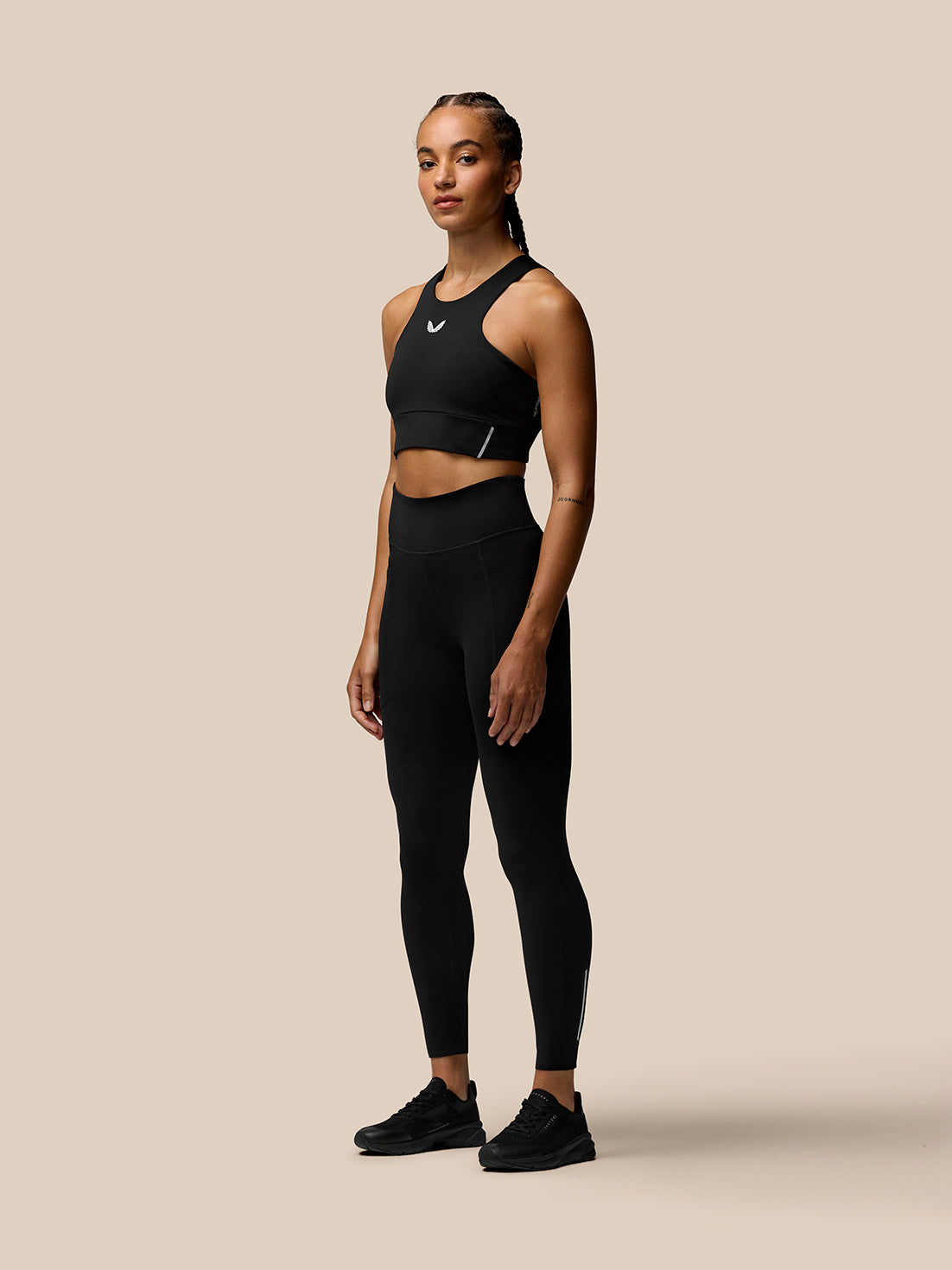 Full-body shot of a woman modeling the black Apex Training Sports Bra with matching leggings.