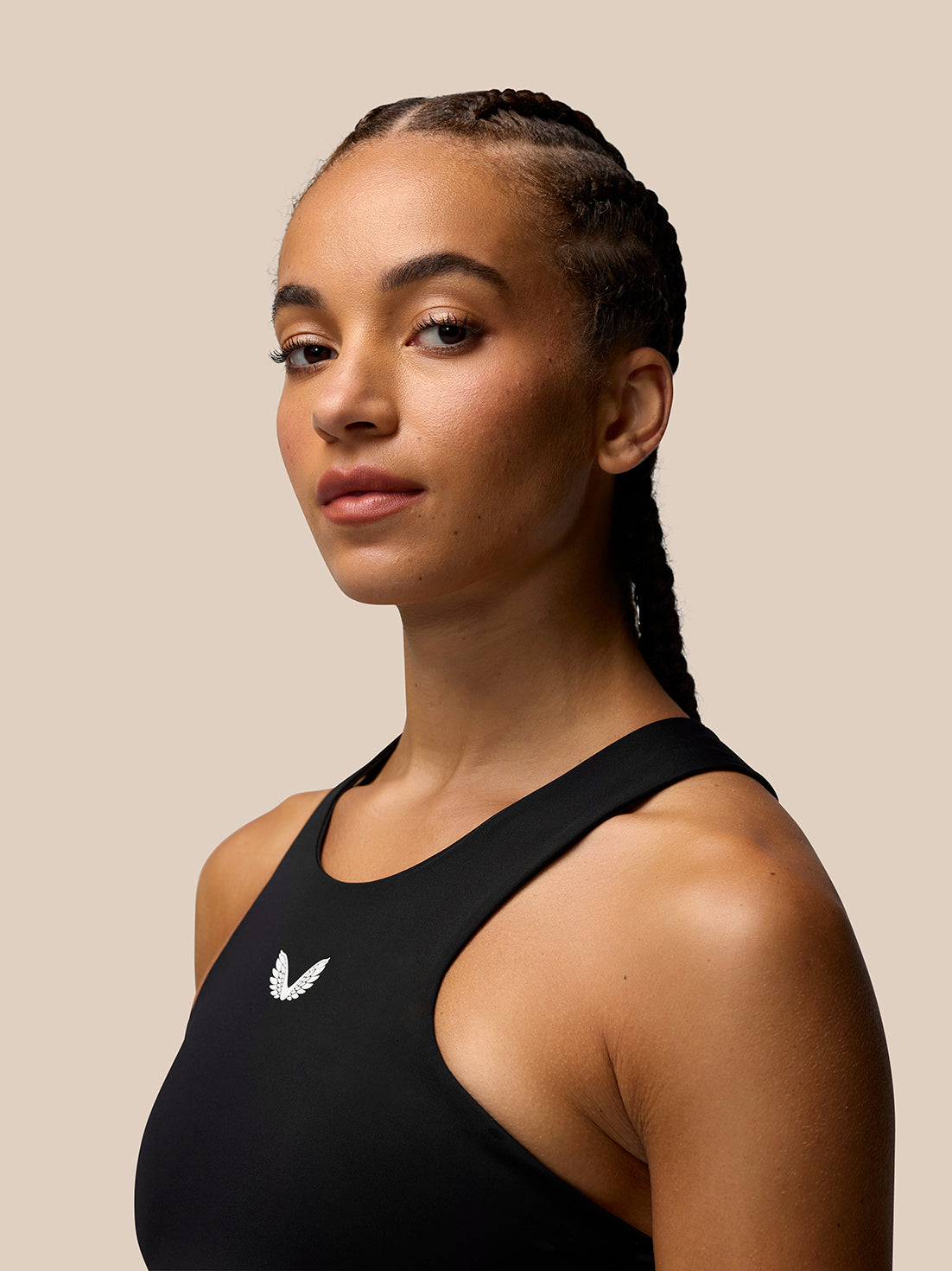 Three-quarter view of a woman in the black Apex Training Sports Bra with scoop neckline and chest logo.