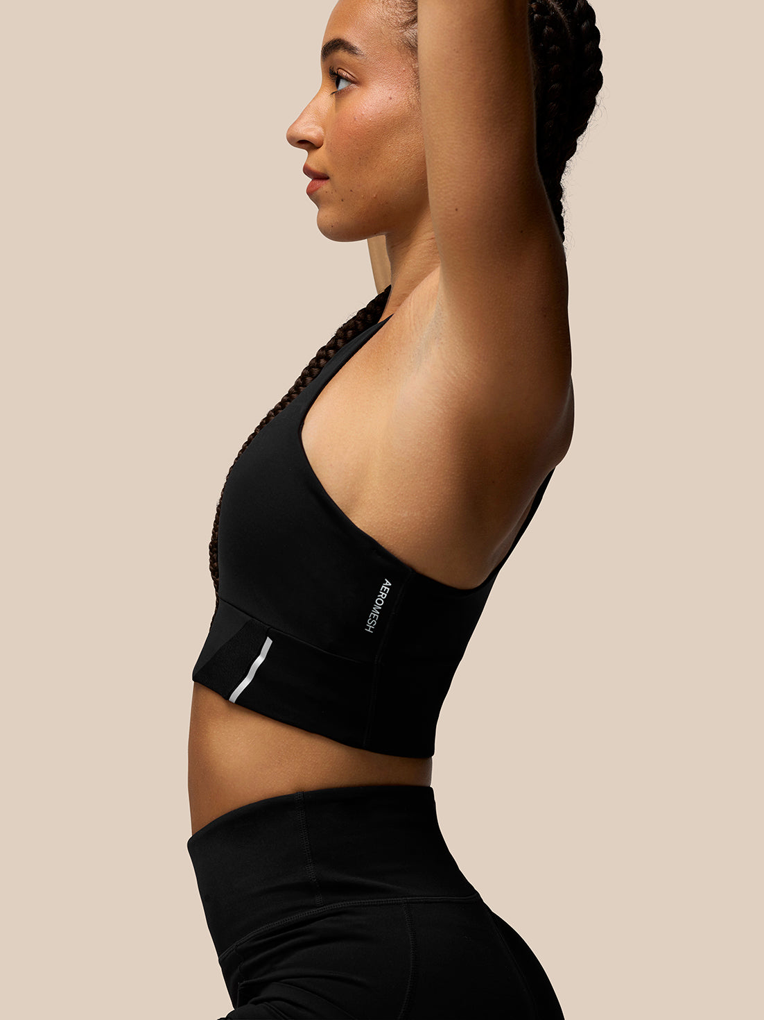 Profile of a woman wearing the black Apex Training Sports Bra with racer back and breathable underband.