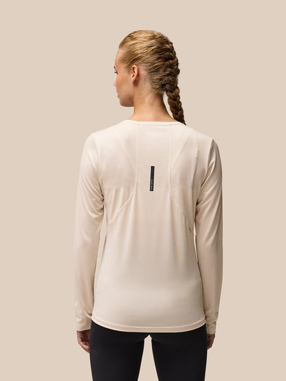 Back view of beige Flow Movement long sleeve tee on a model highlighting the dropped back hem and seam details
