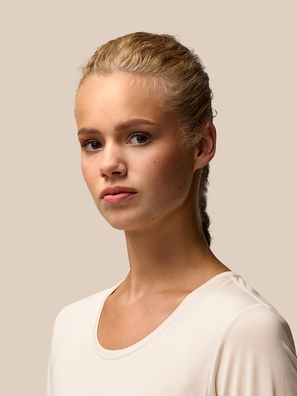 Full-body front view of a model wearing beige Flow Movement long sleeve top with black leggings.