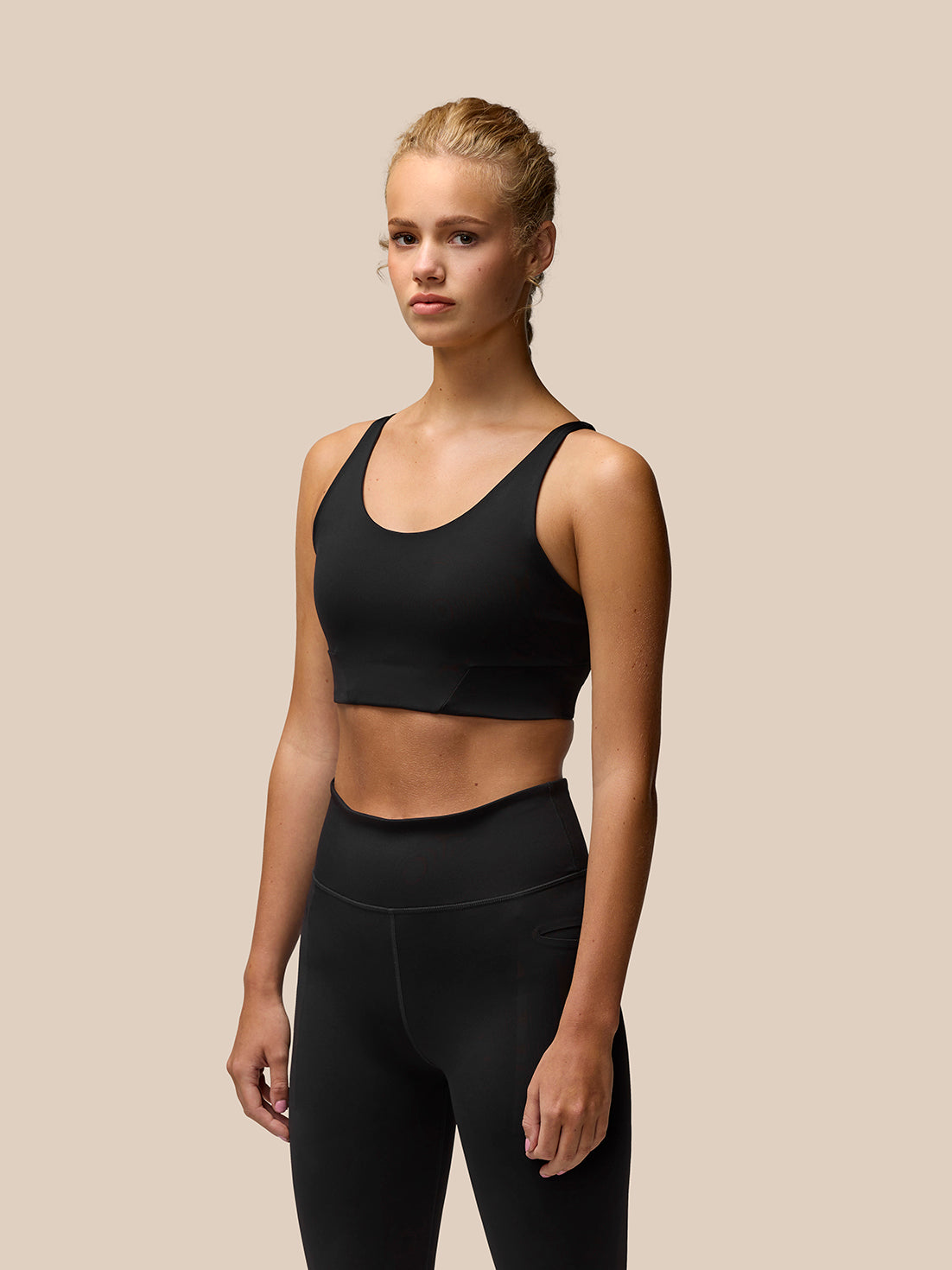 Flow Training Sports Bra in black cropped length with adjustable straps and removable cups worn by model.