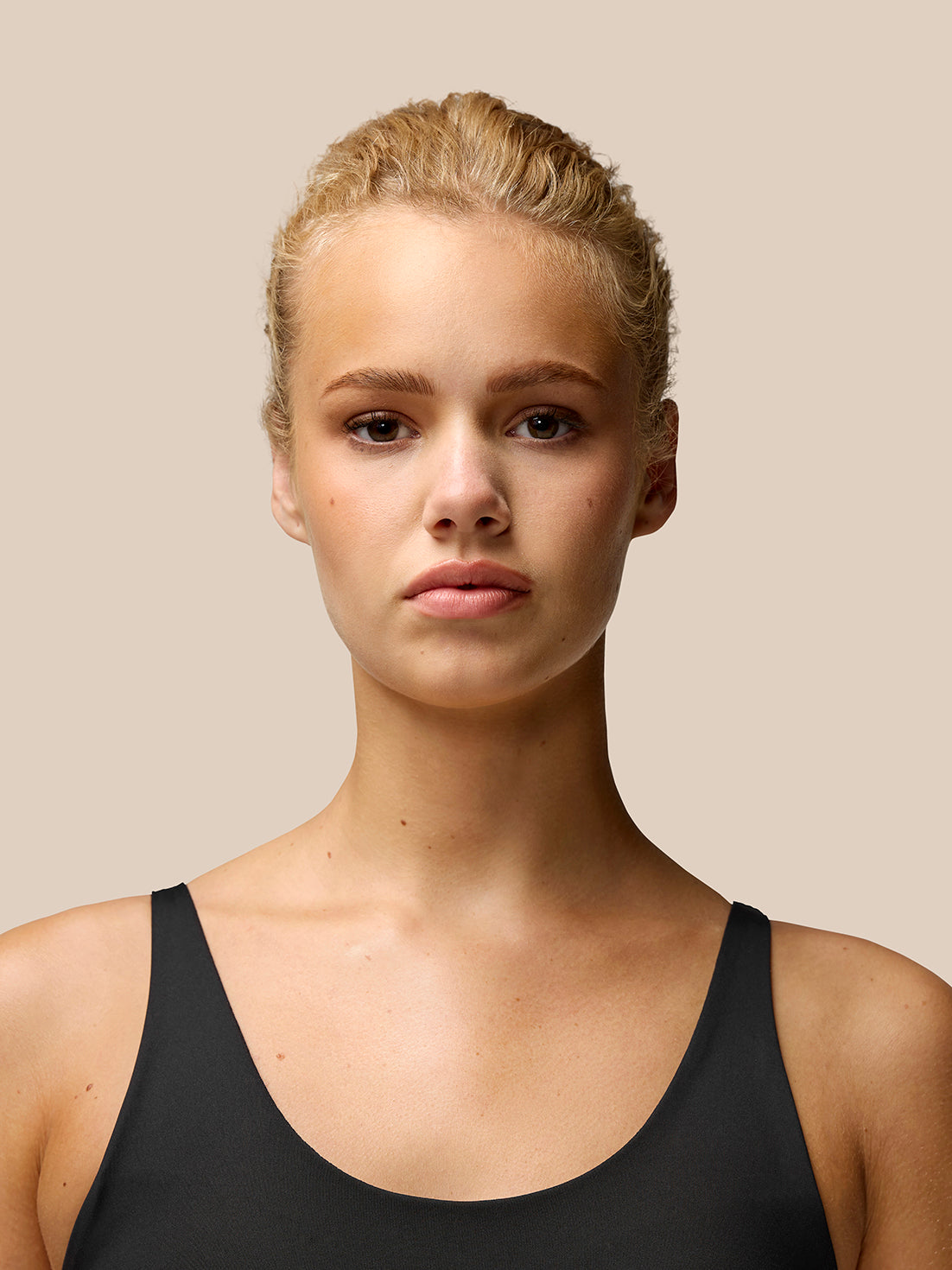 Portrait of a model wearing Flow Training Sports Bra in black with thin shoulder straps.