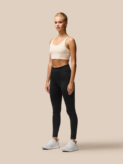 Back view of beige cropped Flow Training Sports Bra with slim straps and back branding tag