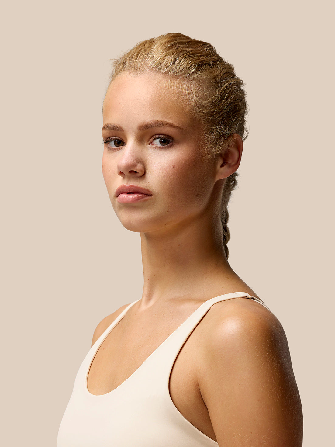 Three quarter profile of a model wearing beige Flow Training Sports Bra with slim straps.