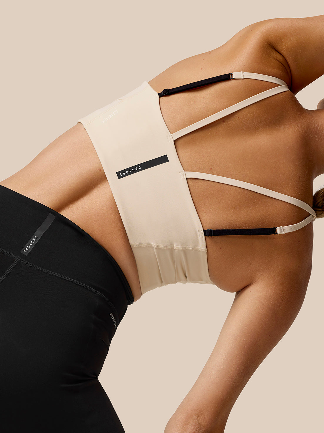 Back view of Flow Training Sports Bra in beige showing multiple slender straps with a black adjustable strap across the back.