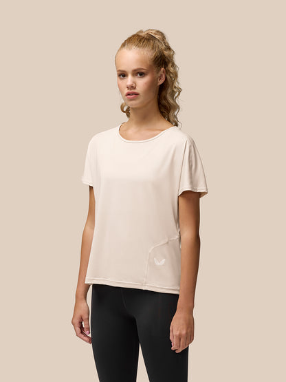Front view of a woman in beige Flow Training T Shirt with a small Castore logo at the left hip
