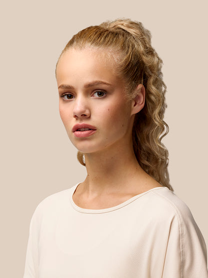 Close-up profile of a model wearing a beige Flow Training T-Shirt, showing a crew neck and soft breathable fabric.