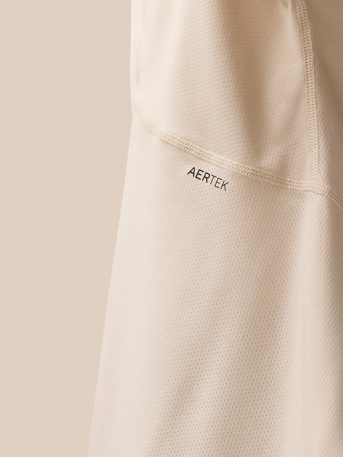 Close-up view of back area of beige Flow Training T Shirt showing AerTek branding and mesh texture.