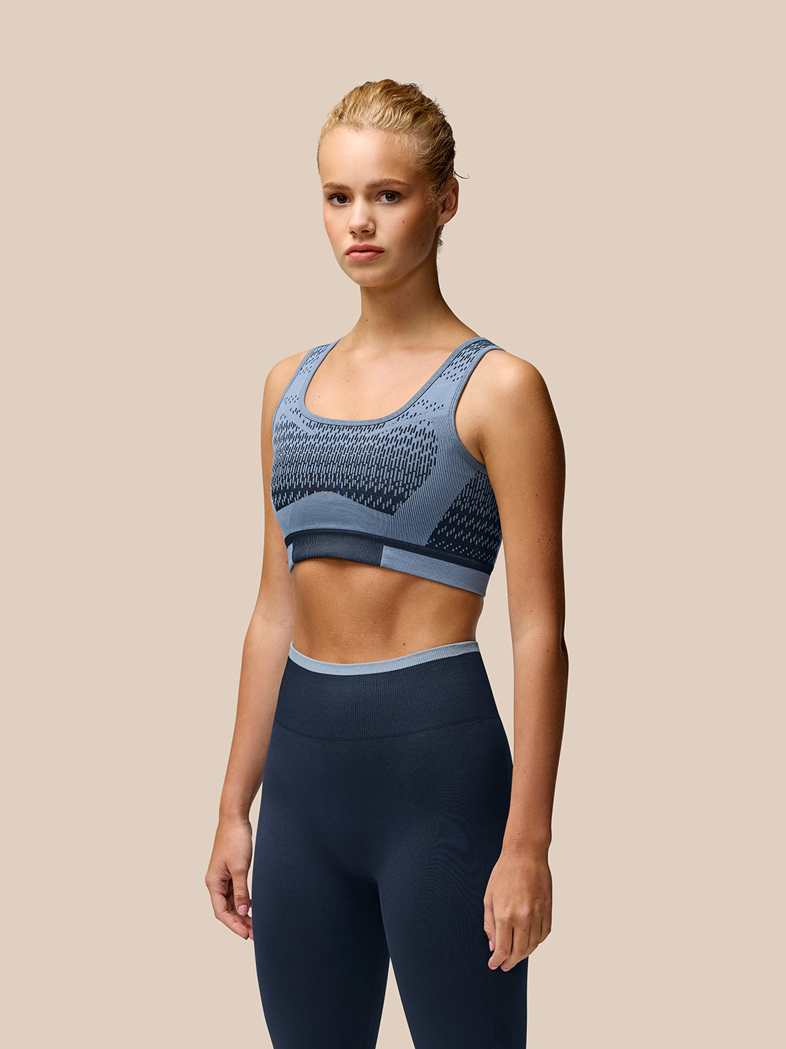 Female model wearing Flow Training Sports Bra in midnight navy with matching leggings