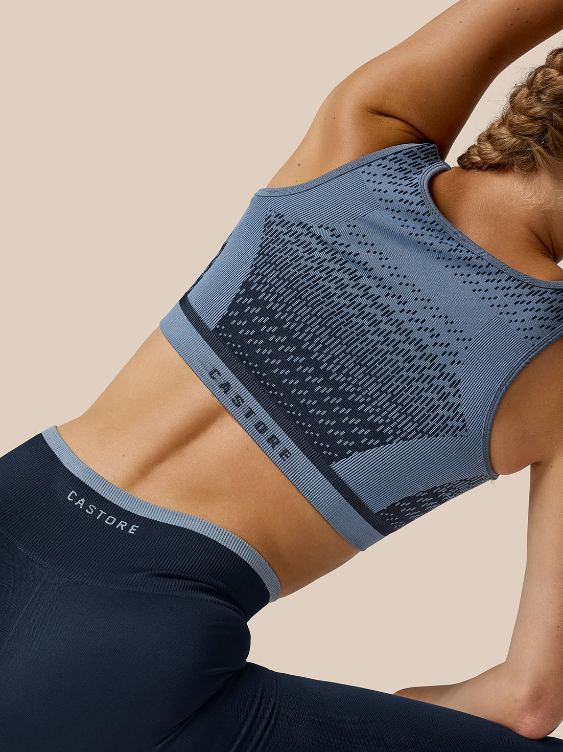Back angled view of a model in the Flow Training Seamless Crop Sports Bra with the jacquard texture and Castore branding on the back band