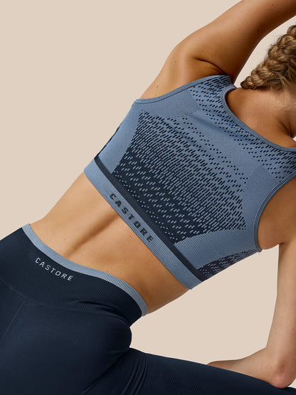 Back angled view of a model in the Flow Training Seamless Crop Sports Bra with the jacquard texture and Castore branding on the back band