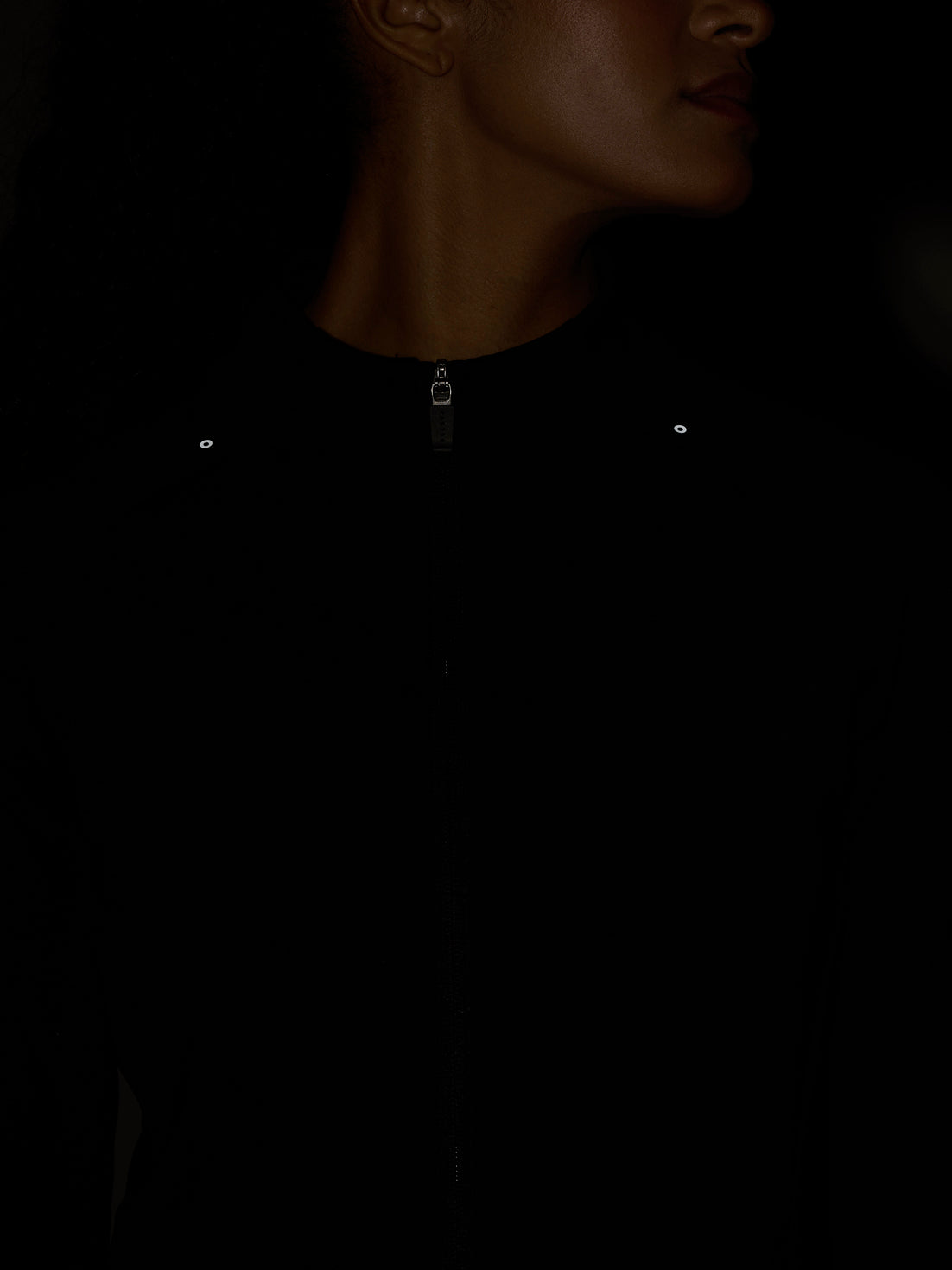 Close up of a black Zone Training Top with a front zip and reflective chest eyelets