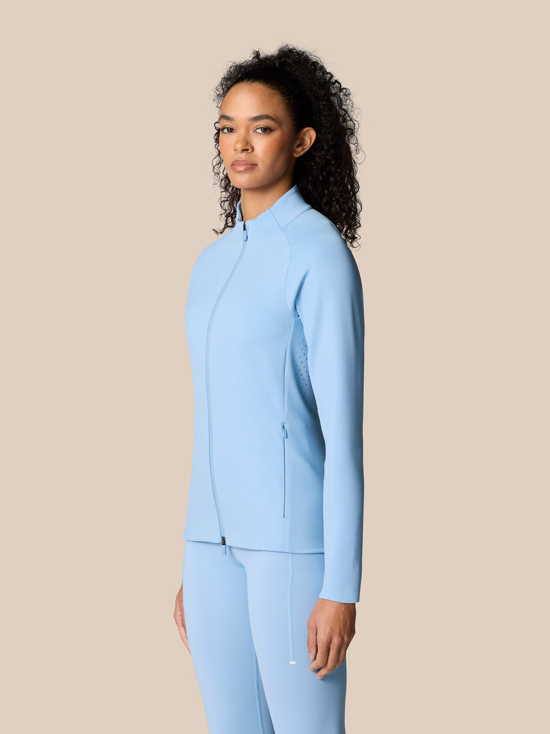 Side view of a model wearing a sky blue Zone Training Top full zip jacket with bonded hems.