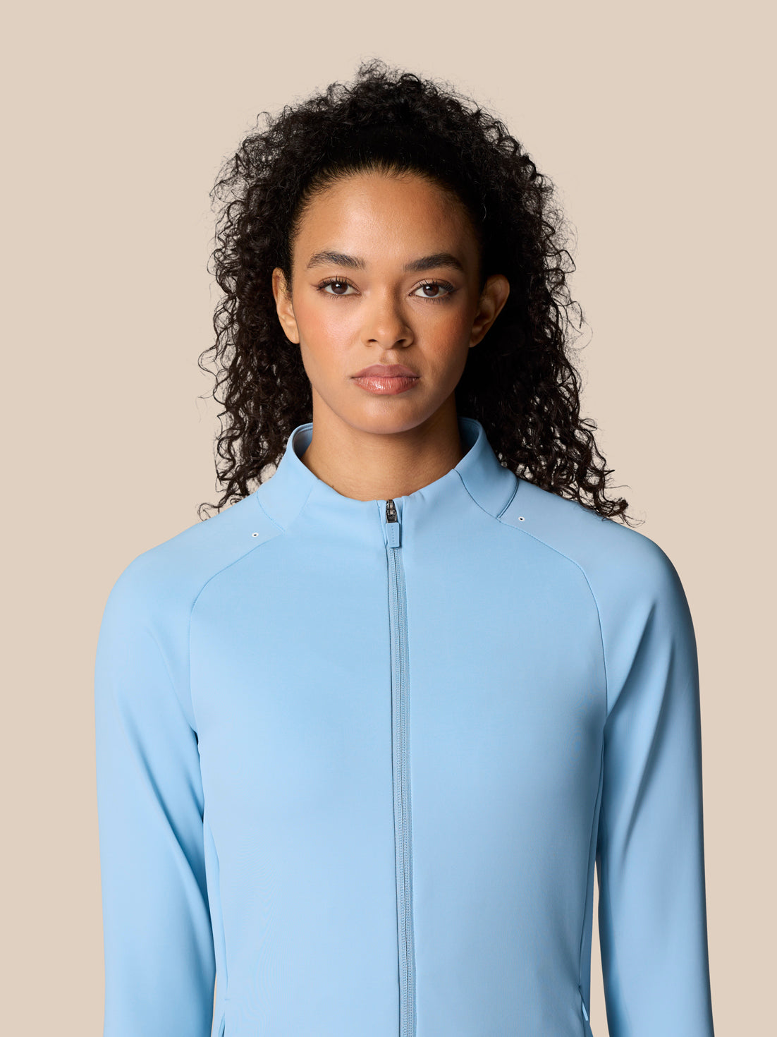 Close up of female model wearing the sky blue Zone Training Top jacket, highlighting the high collar and full zipper.