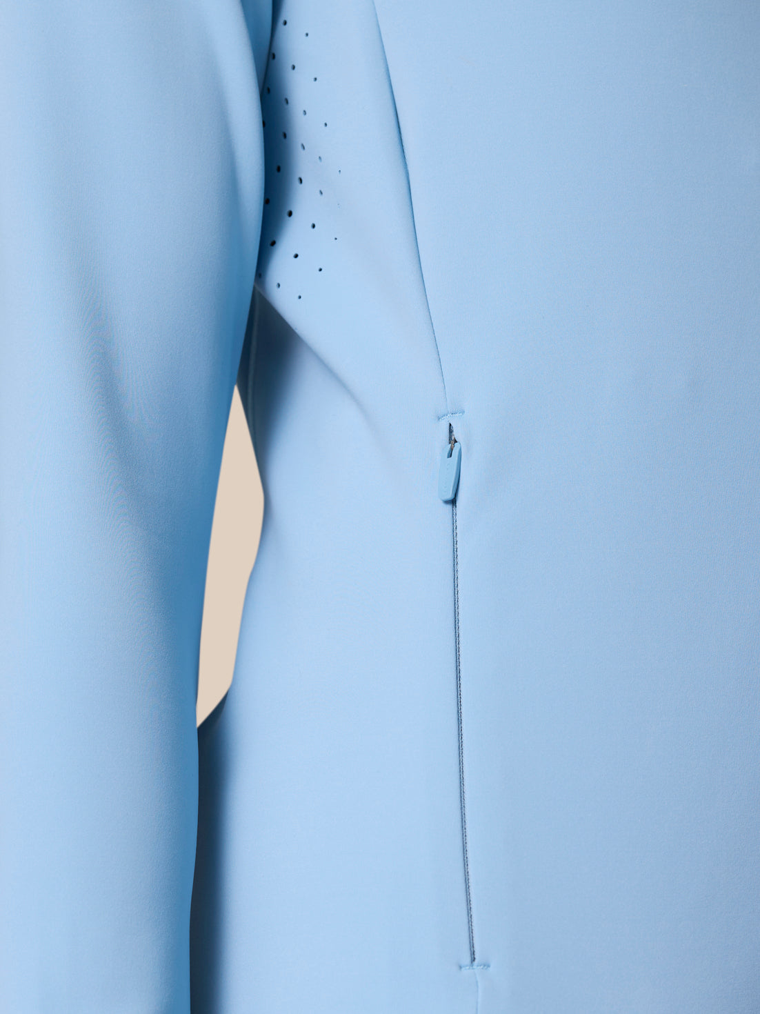Close-up of the sky blue Zone Training Top showing vent holes and a side zipper.