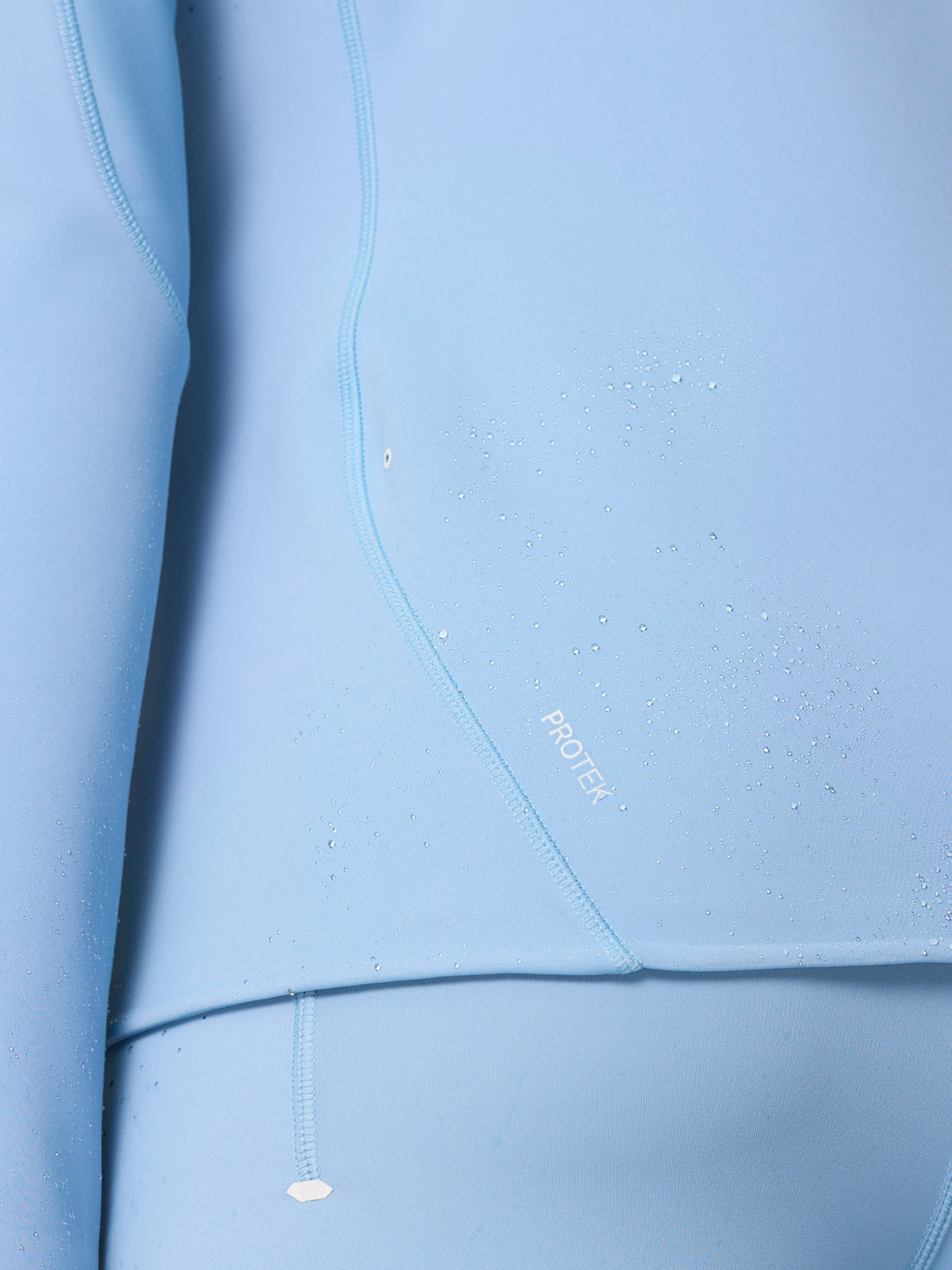 Close-up of fabric with water droplets beading and the ProTek logo on the Zone Training Top.