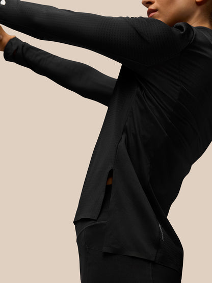 Side view of a model wearing the black Apex Training top, featuring textured fabric and side slit for mobility.
