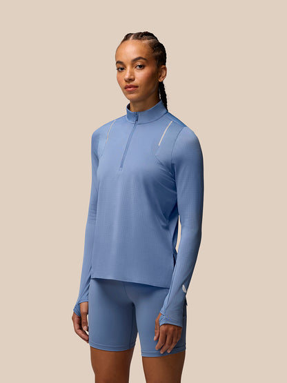 Woman wearing light blue Apex Training long sleeve top with funnel collar and thumbholes