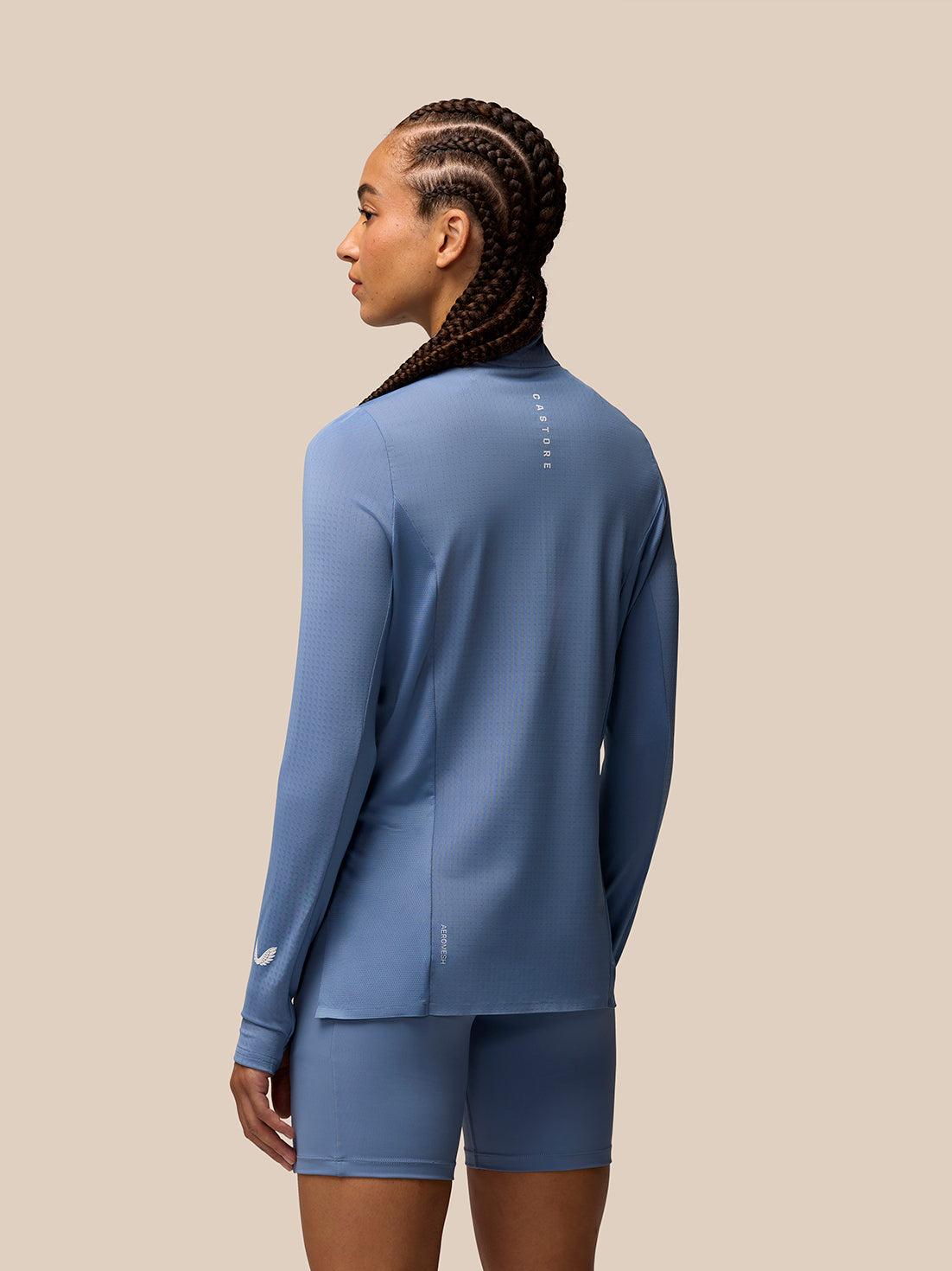Back view of a model wearing light blue Apex Training long sleeve top with zip detail