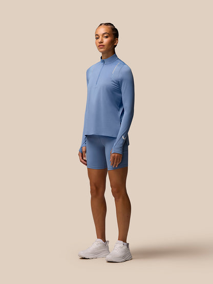 Model wearing light blue Apex Training long sleeve quarter zip top with matching shorts against a beige backdrop.