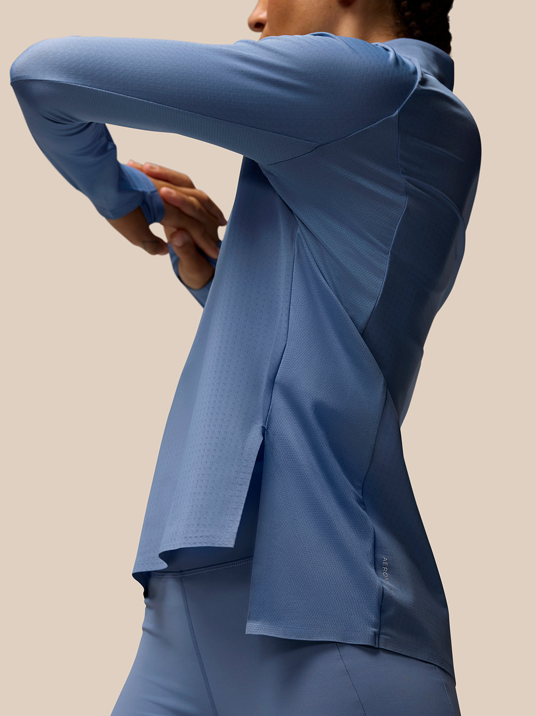 Side profile of a model wearing a light blue Apex Training long sleeve top showcasing contoured panels and fit