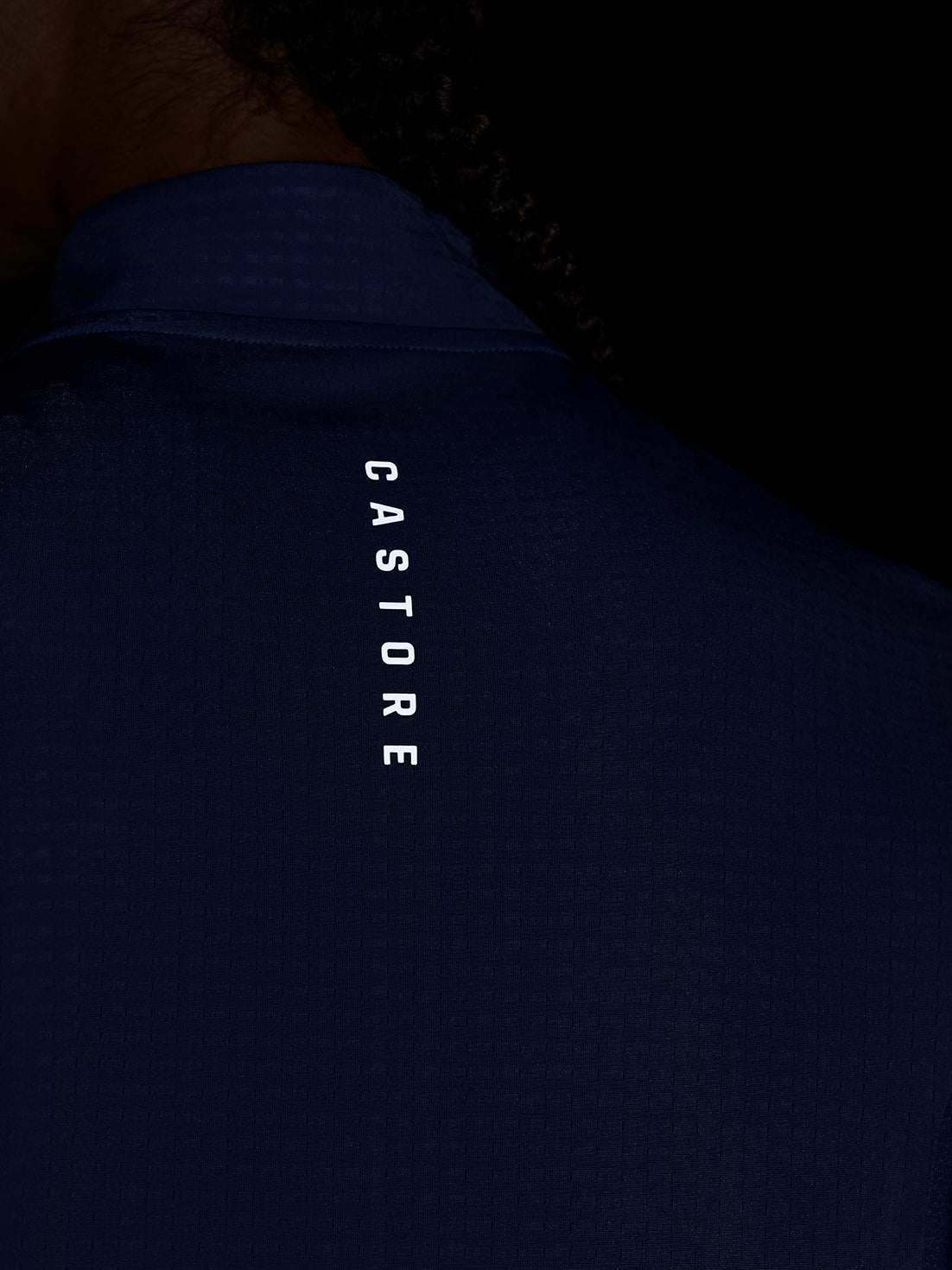 Back view of a dark blue Apex Training top with vertical Castore branding along the neck