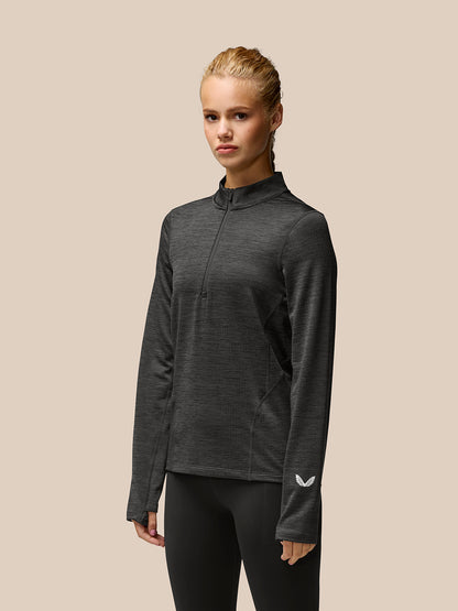 Female model wearing Flow Training fleece half zip top in dark charcoal with funnel collar and front zip