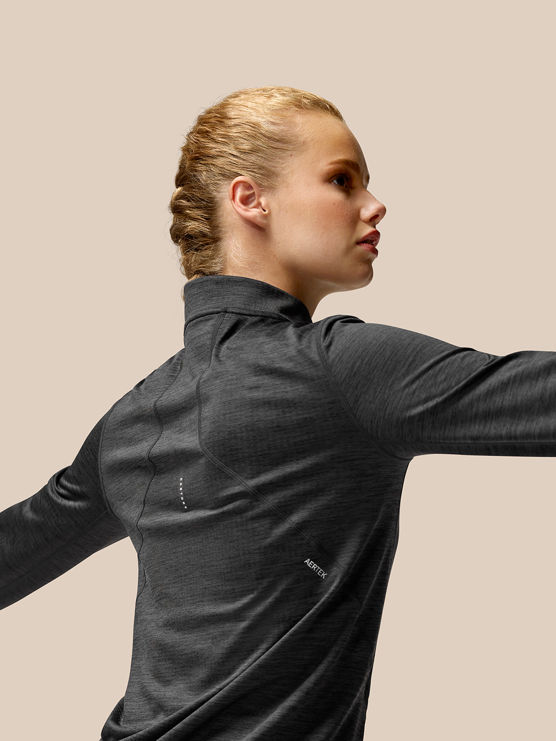 Three-quarter rear view of a woman in Flow Training fleece half zip top with AerTek branding visible on the back.