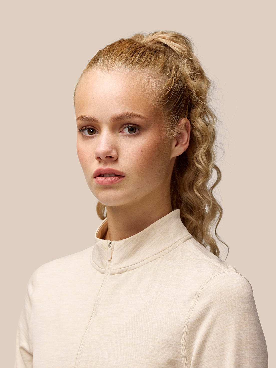 Model wearing Flow Training beige fleece half zip top with funnel collar and front half zip.