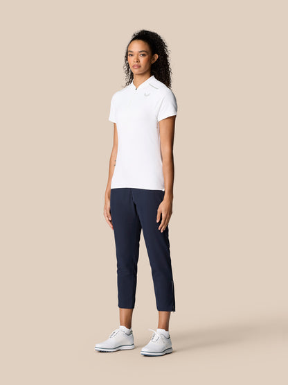 Full body of a woman modeling white polo and midnight navy 7/8 golf trousers