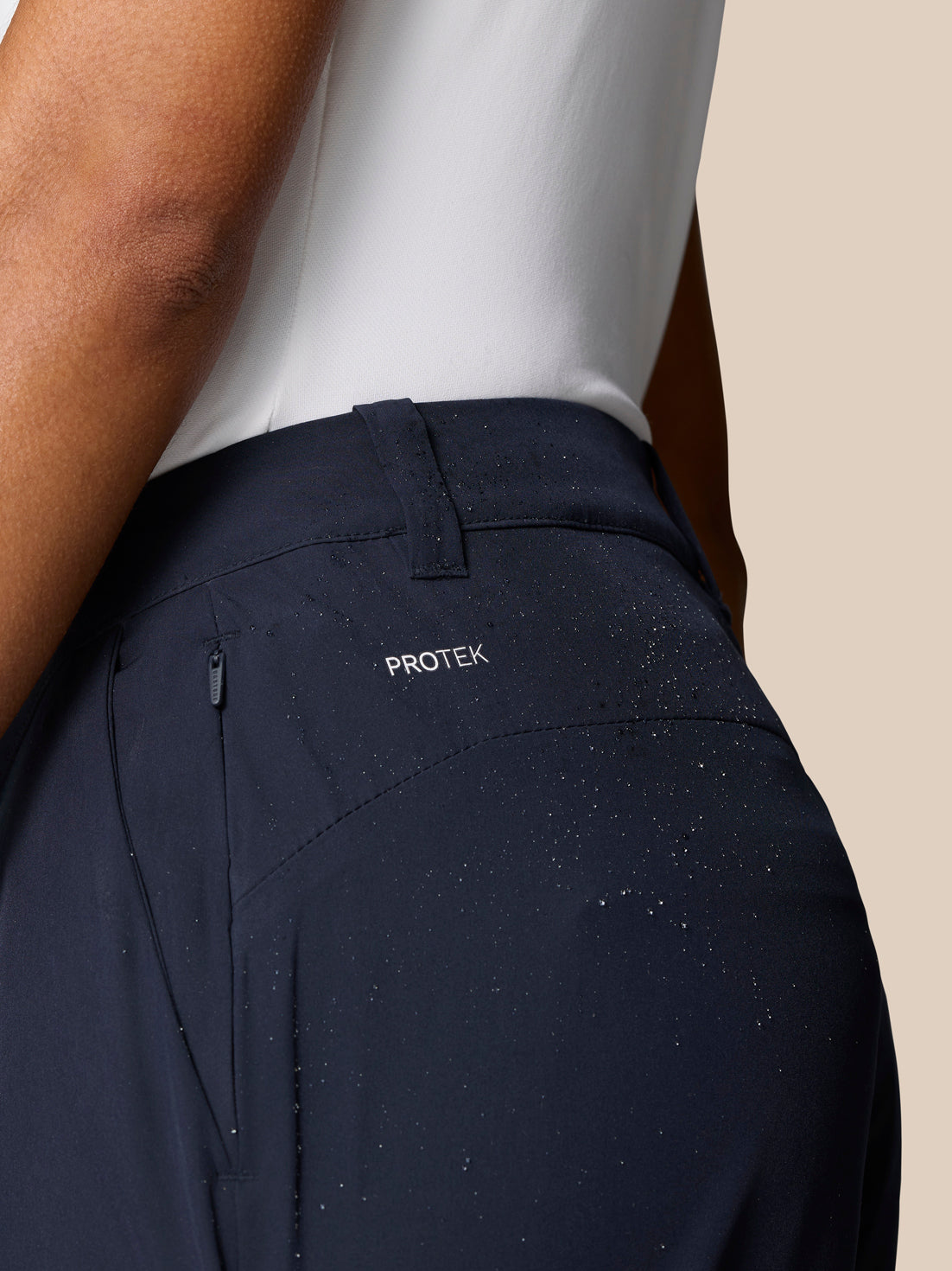 Close-up of navy Club Golf Trousers waist showing ProTek branding and water droplets on the fabric