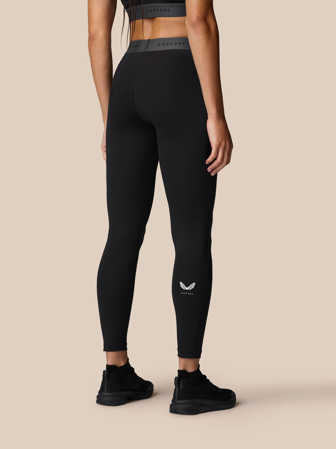 Back view of a model wearing black Adapt Training Leggings with a small Castore logo at the ankle.