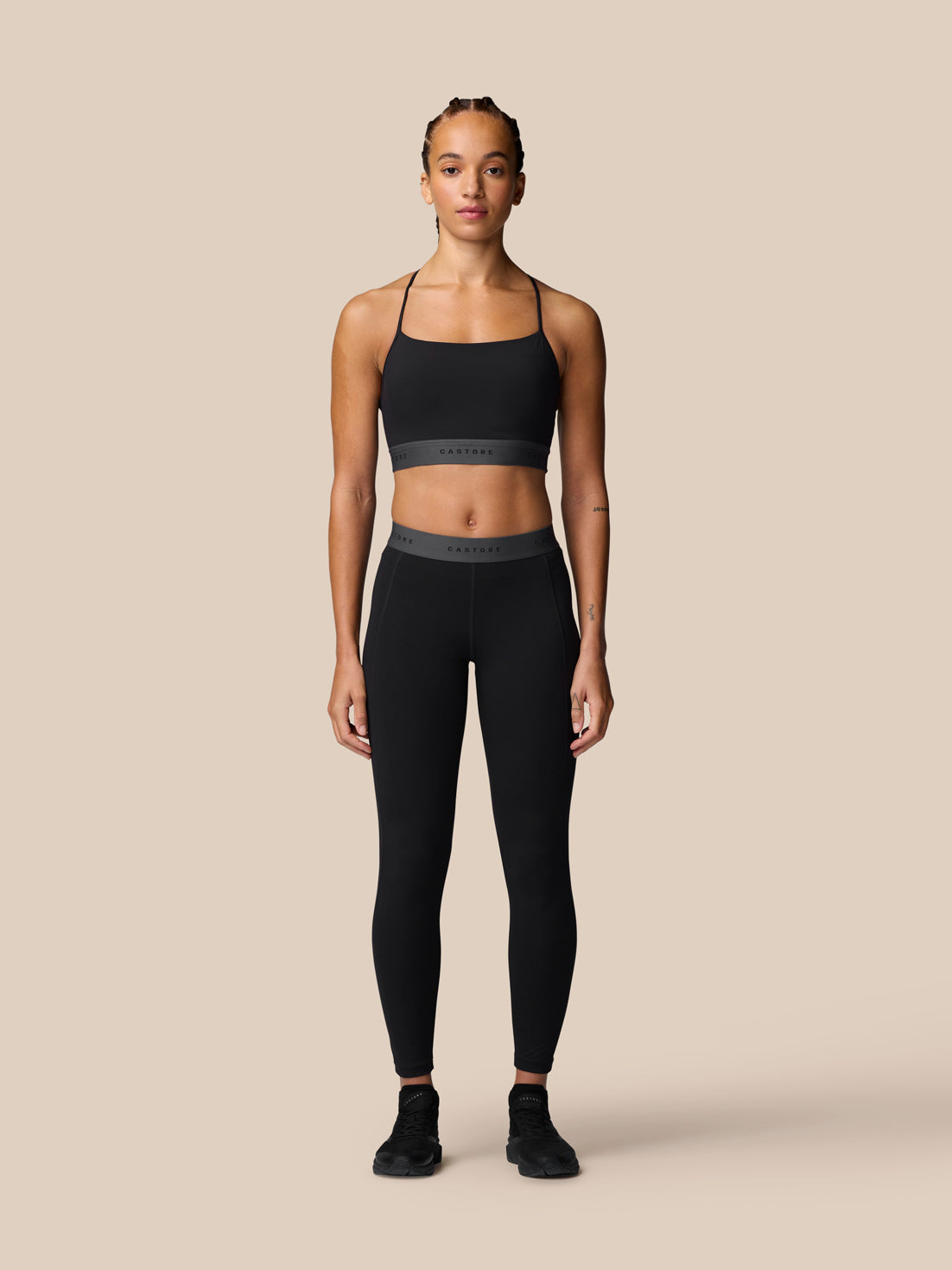 Front view of a model in black Adapt Training Leggings with a grey waistband and sports bra ready for a workout.