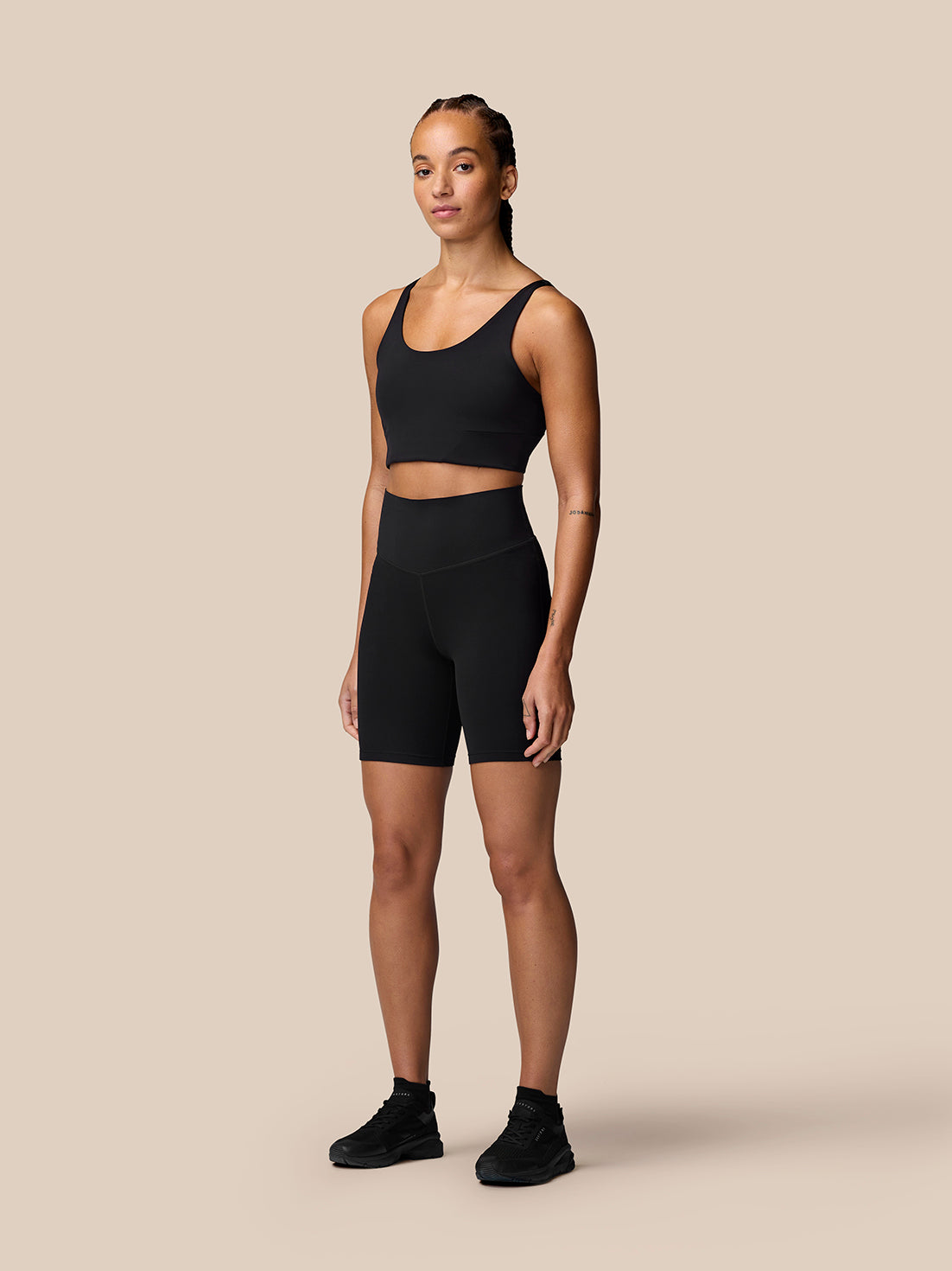 Full-body shot of a model wearing black Apex Training Shorts with a matching black sports bra ready for workouts