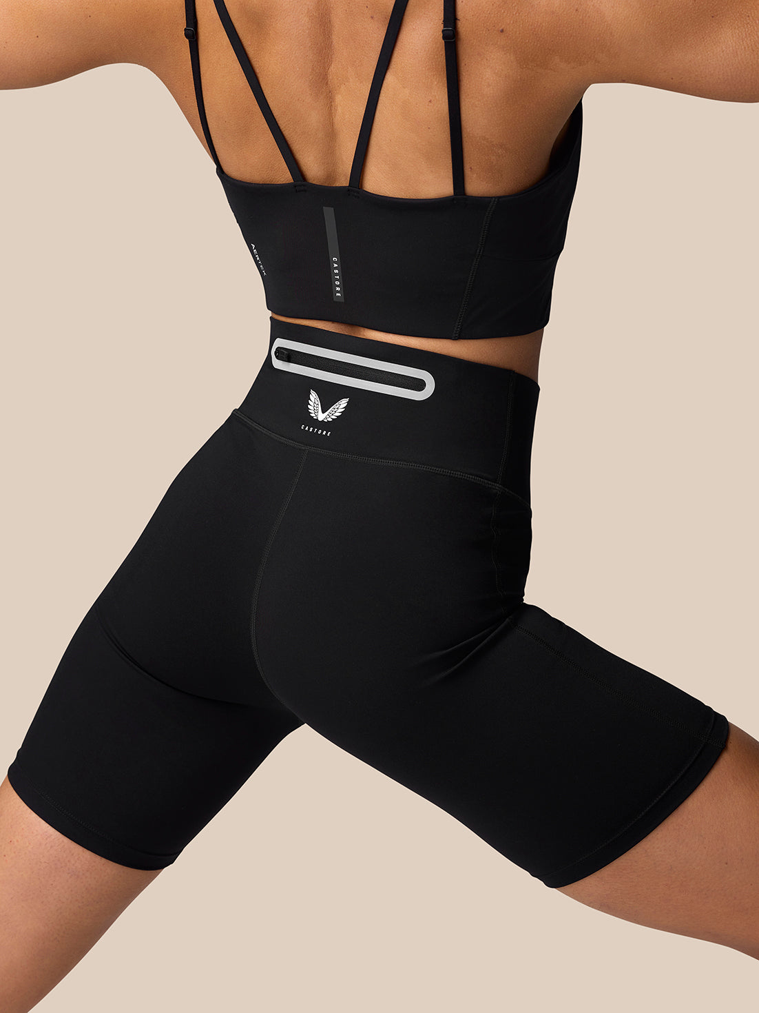 Back view of a woman in black Apex Training Shorts with a white reflective waistband bar and Castore branding on the thigh