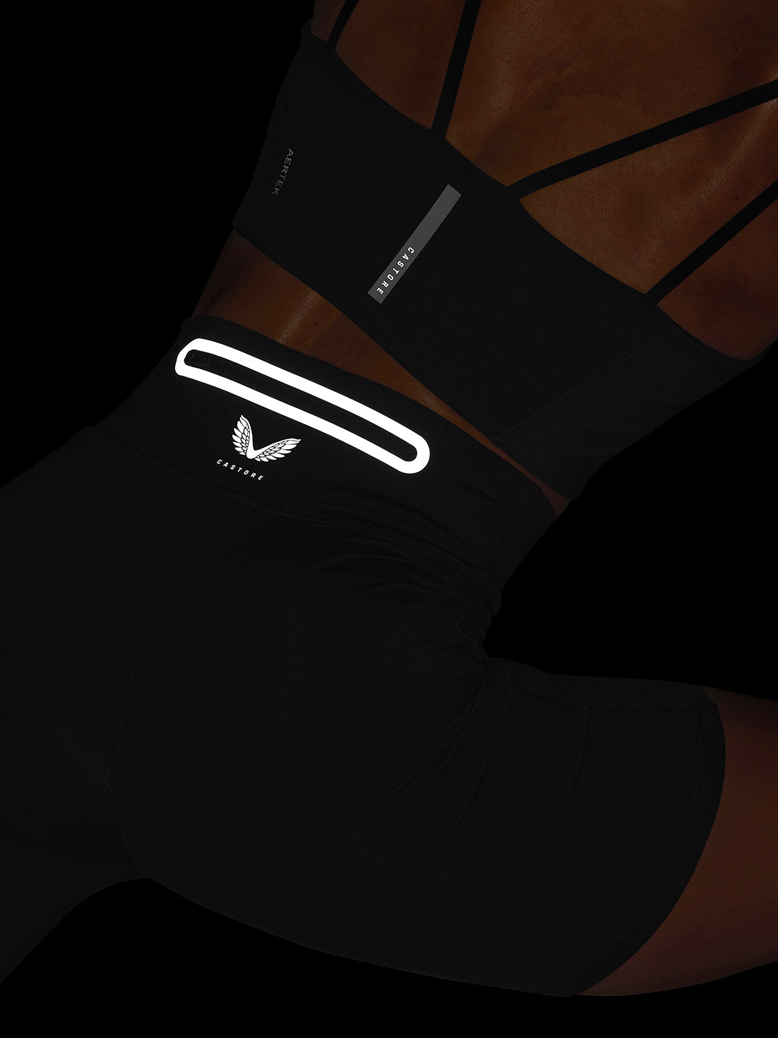 Close-up of black Apex Training Shorts showing the white reflective waistband stripe and Castore emblem