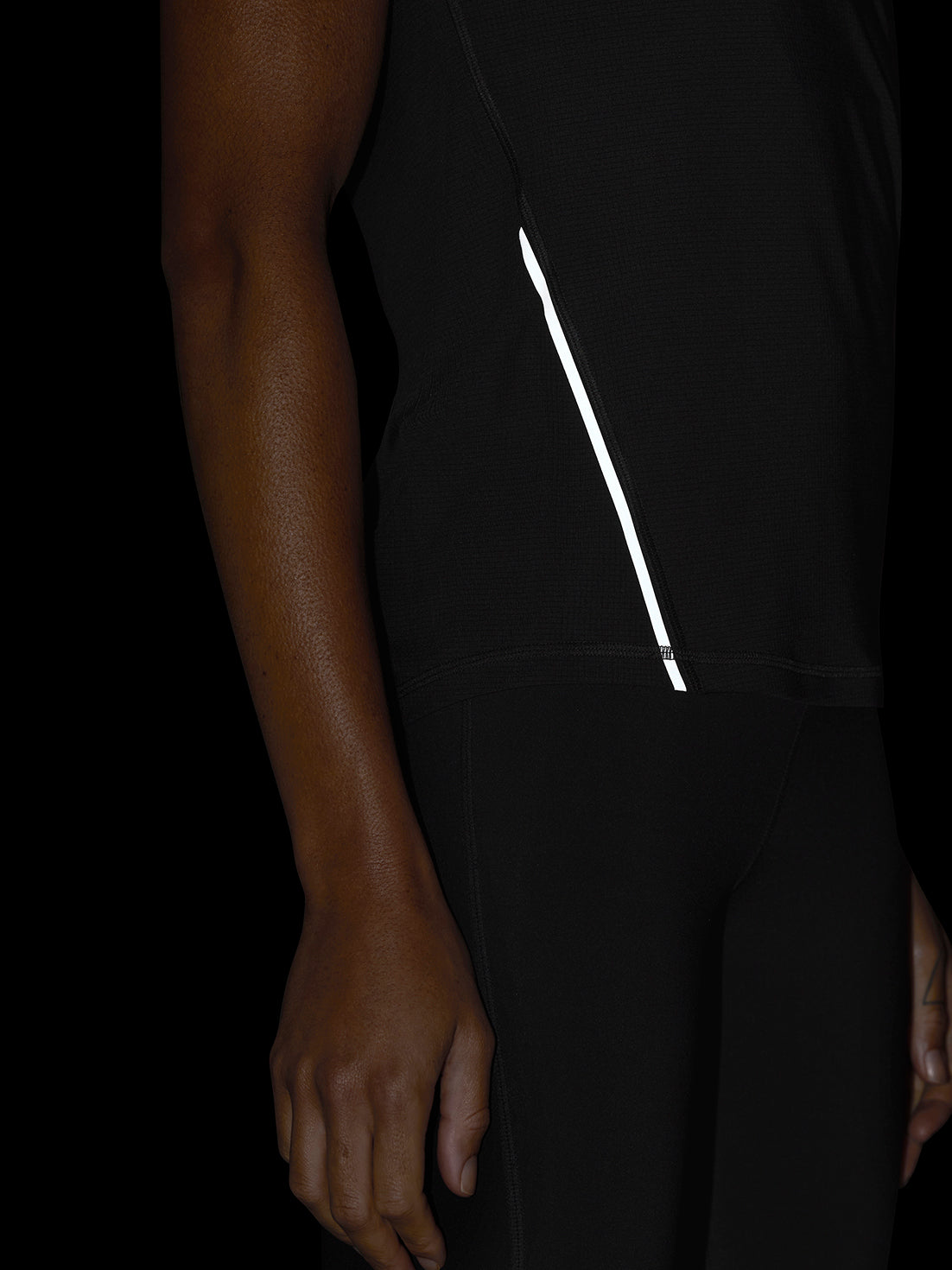 Close-up of black Apex Training T-Shirt side seam showing a white reflective stripe.