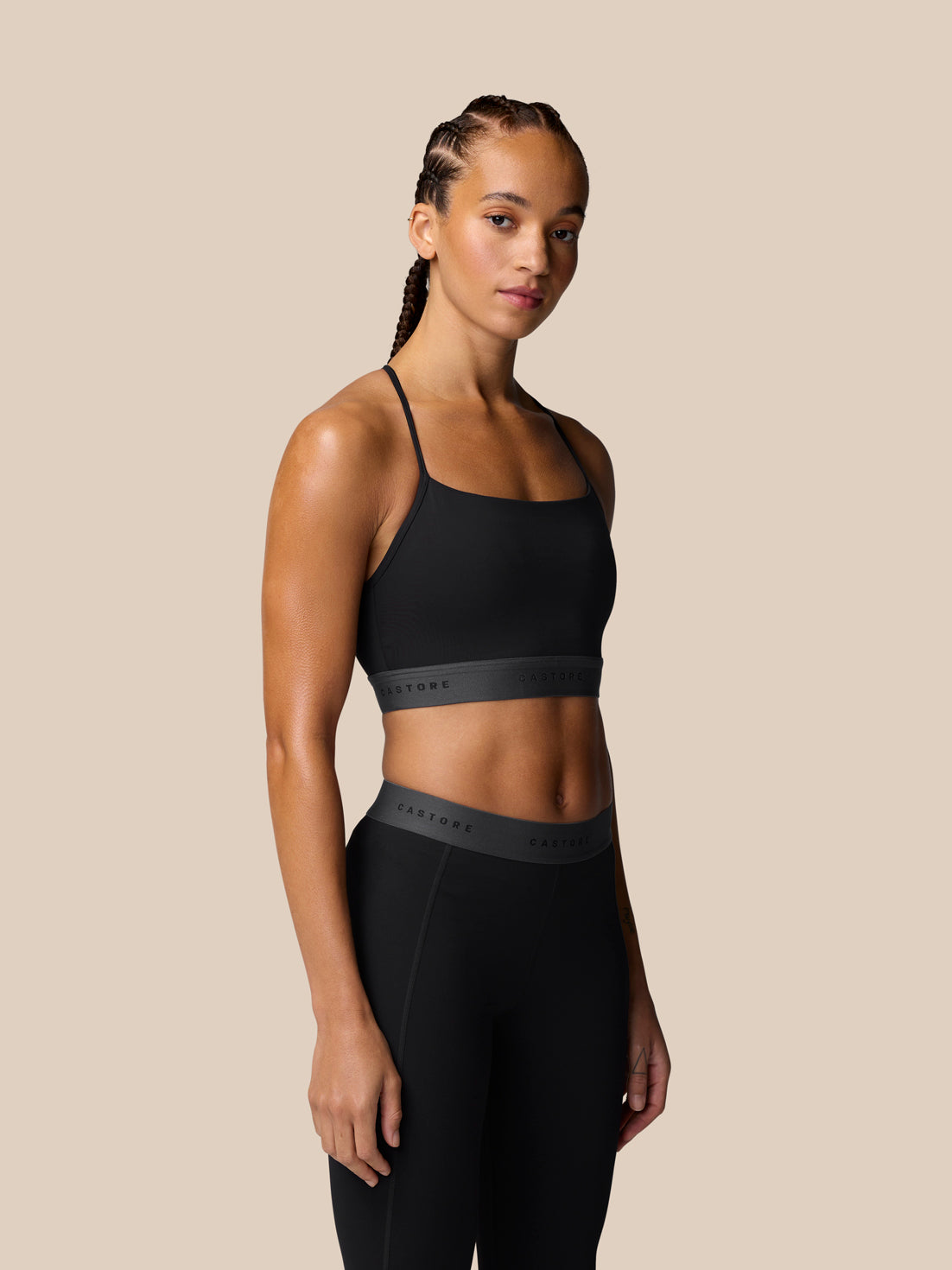Three-quarter back view of model in black Adapt Training Sports Bra with slim straps and logo waistband.