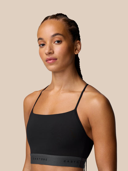 Front view of a model wearing black Adapt Training Sports Bra with thin straps and a grey Castore waistband.